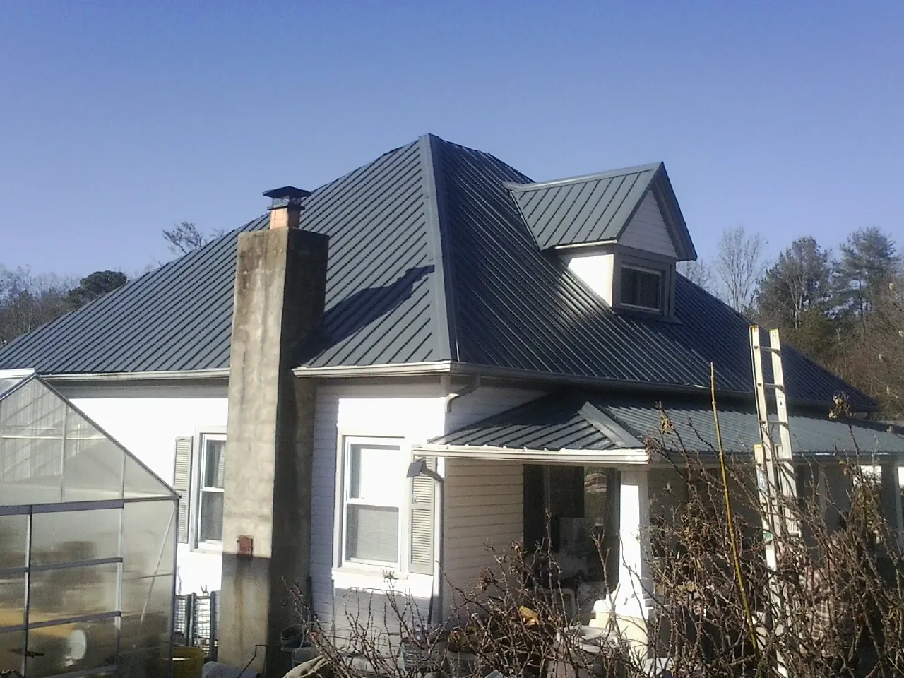Dark blue standing seam metal roof on a white farmhouse with dormer — Slate & Tile Roof Repair by Roofing Brothers in Teachey
