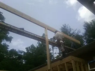 Carpenter setting a ridge beam over a new addition frame — Ice Dam Removal by Roofing Brothers in Teachey