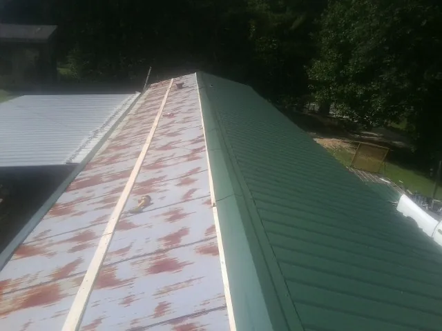 Old rusted panels beside newly installed green metal roofing — Wind Damage Roof Repair by Roofing Brothers in Teachey