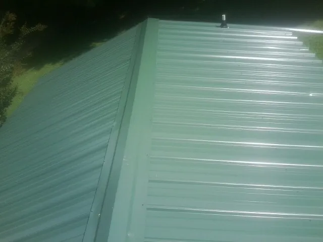 New green metal panels meeting at the ridge of a roof — Flat Roof Repair work by our crew in Teachey