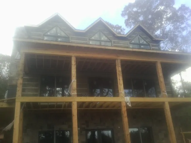 Dormers and porch framing on a large log home under construction — Roof Coating work by our crew in Teachey