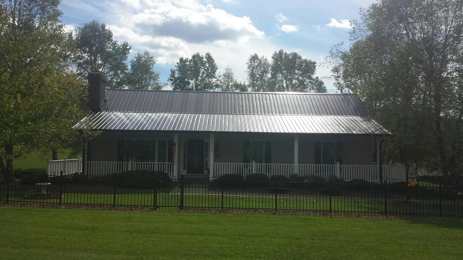 Gray metal roof on a brick ranch with a full width front porch — Gutter Guard Installation work by our crew in Teachey