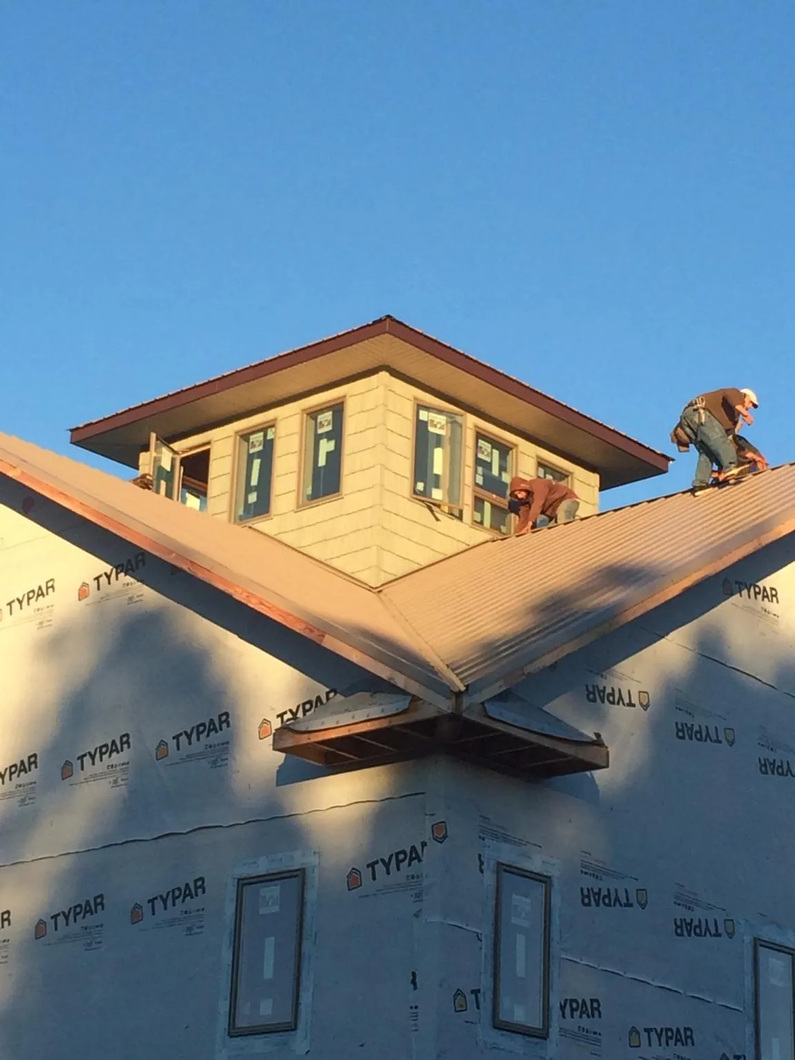 Roofers working around a rooftop cupola on a new metal roof at sunset — Roof Waterproofing in Teachey by Roofing Brothers